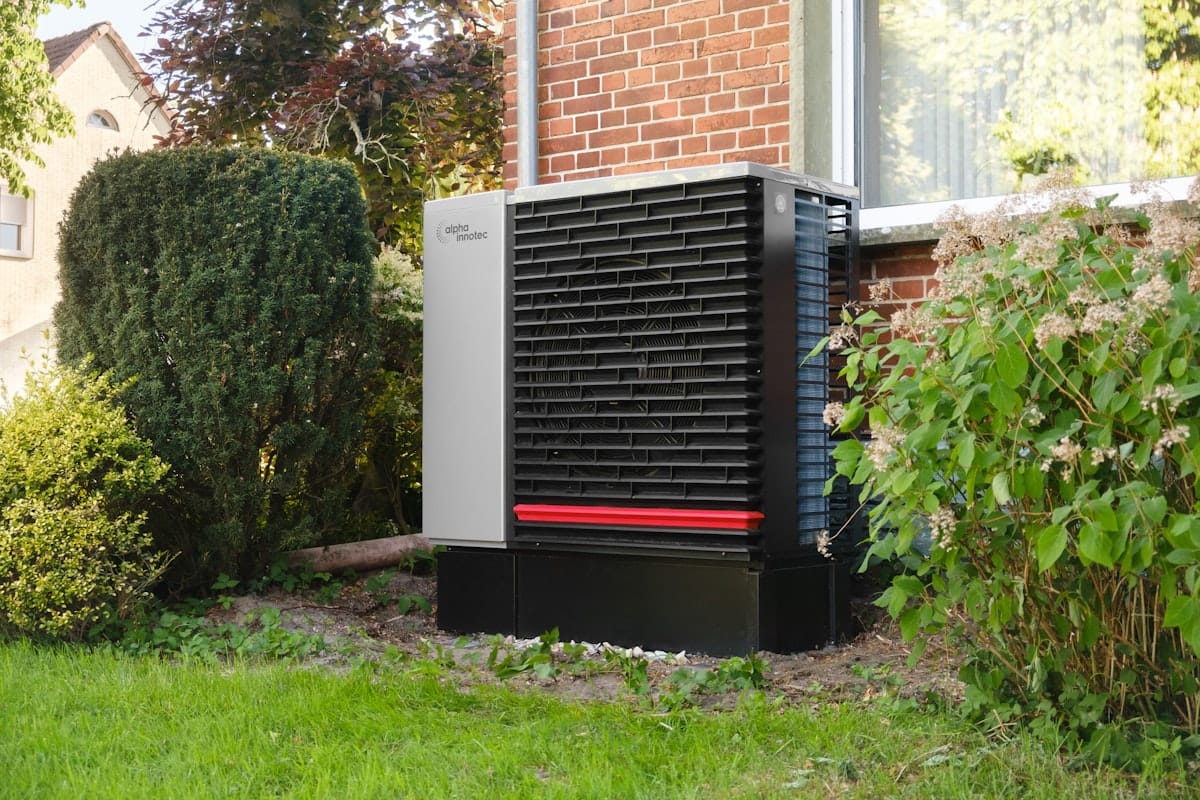 An air-source heat pump outdoor unit installed beside a UK brick wall